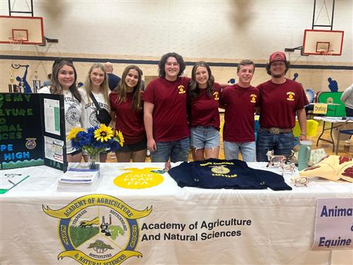 Seven agriculture academy students standing in front of their table display 