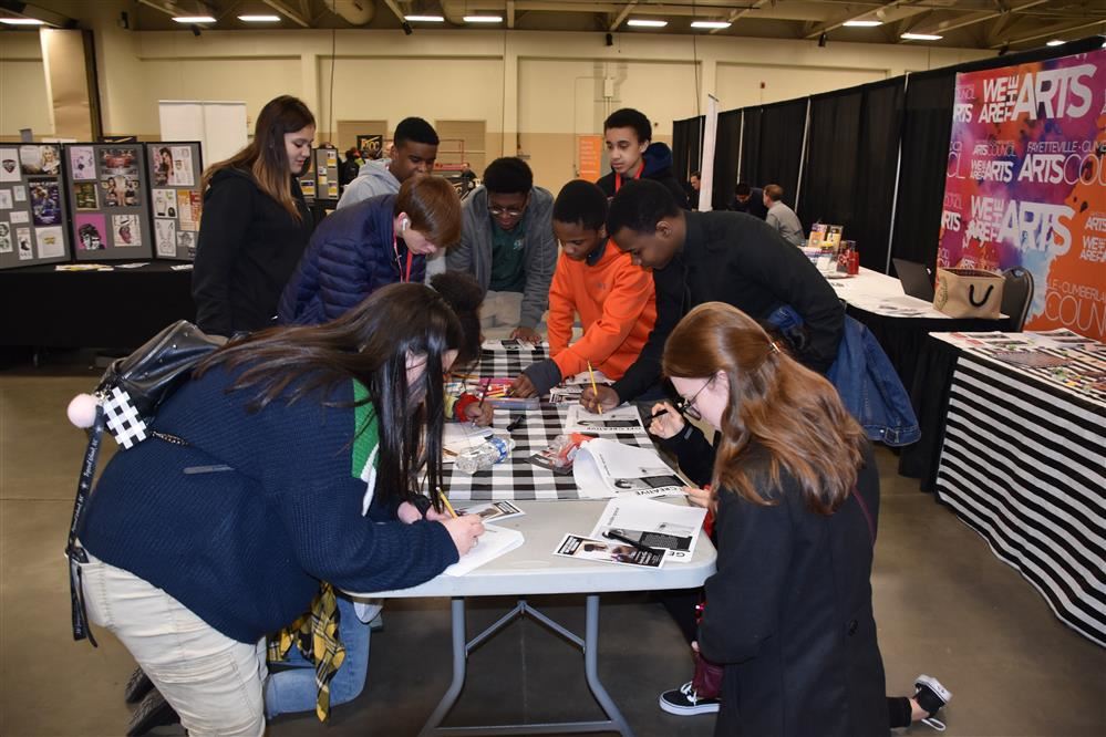 Multiple students gathered around a table writing