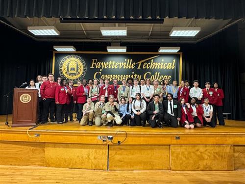 Students posing for a group photo on stage at the Skills USA competition