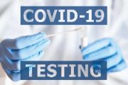  White sign with hands wearing blue gloves and the words COVID Testing